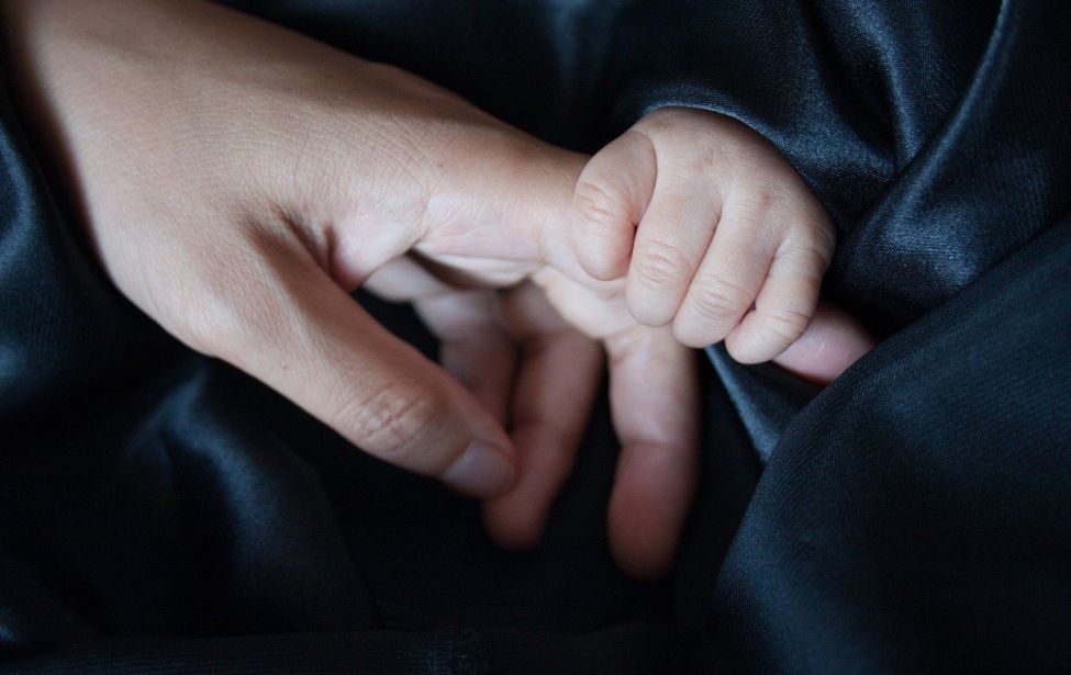 Kinderhand greift nach Hand eines Erwachsenen