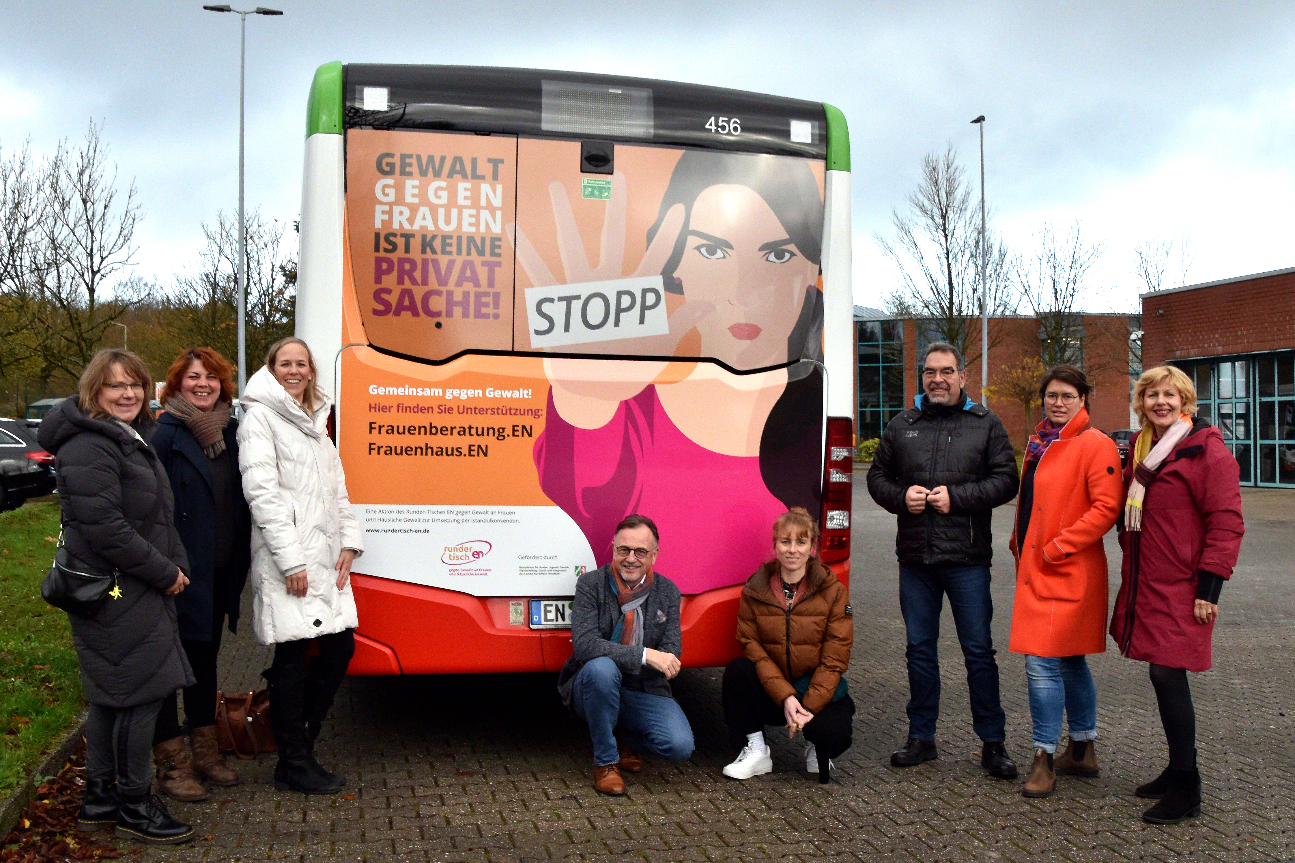 Gruppenportrait von Personen vor einem beschrifteten Bus
