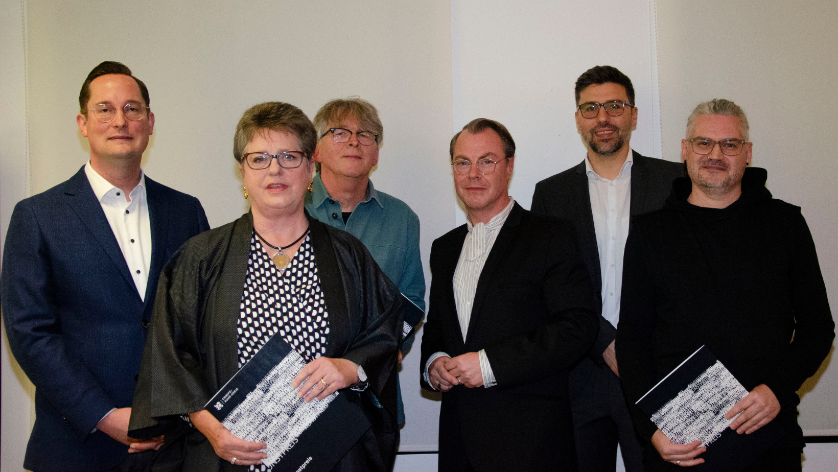 Fotografie von sechs Personen vor einer weißen Wand