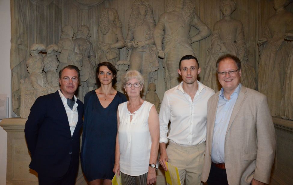 Fotografie von fünf Personen vor einem Kunstwerk