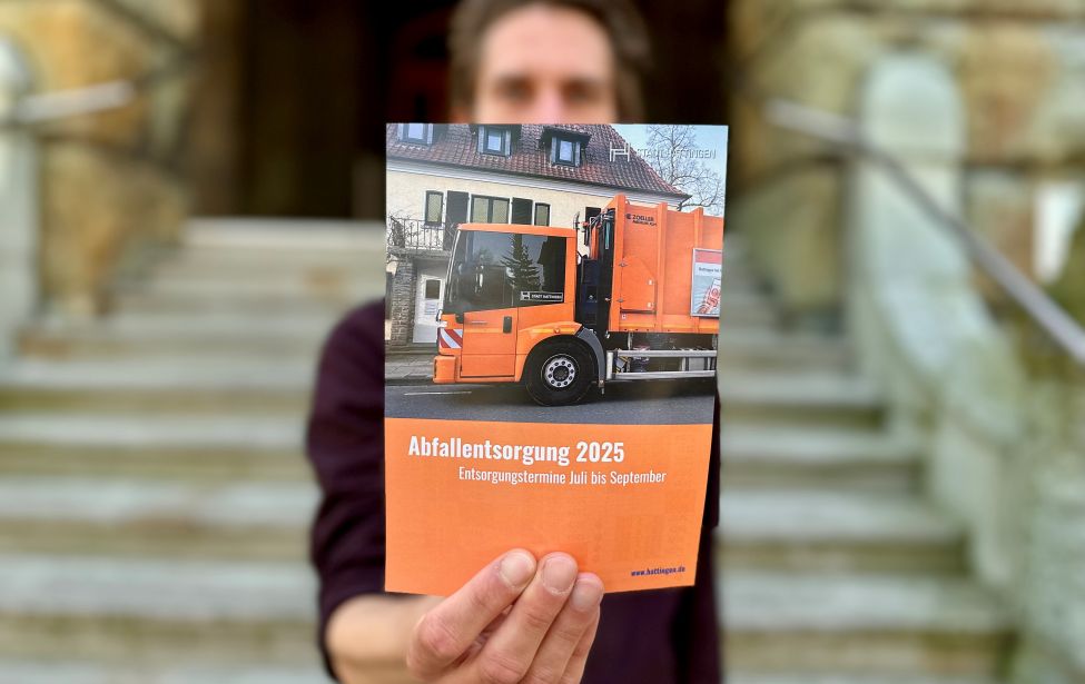 Eine Person hält den Flyer in den Händen hoch