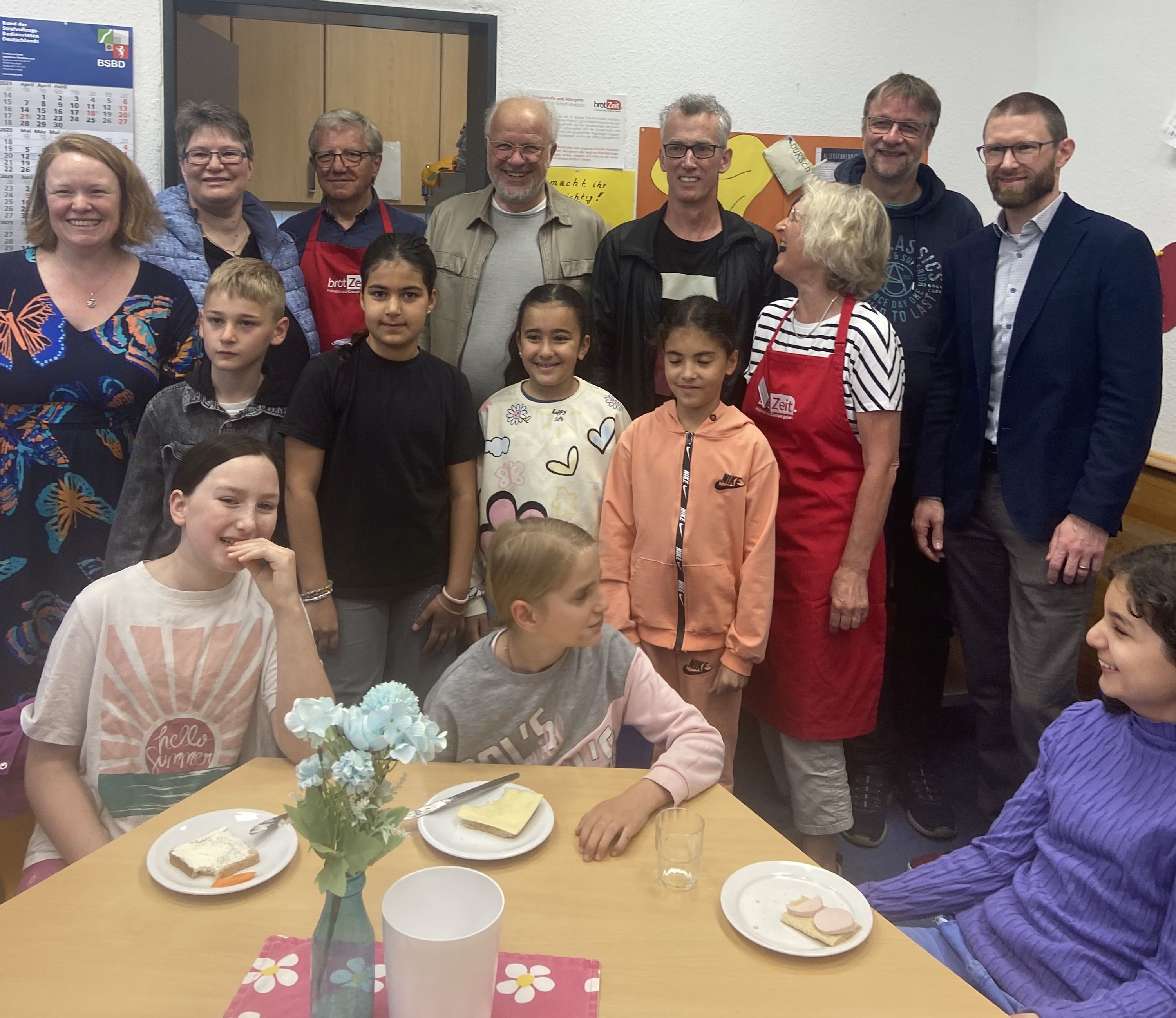 Kinder am Tisch beim Frühstück im Hintergrund eine Menschengruppe