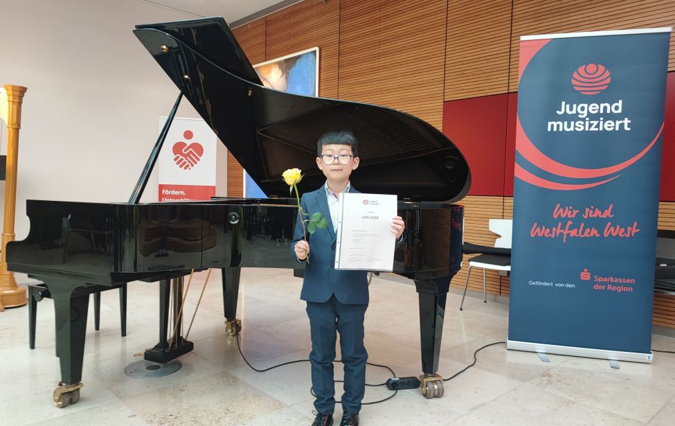Fotografie von dem Schüler vor einem Klavier