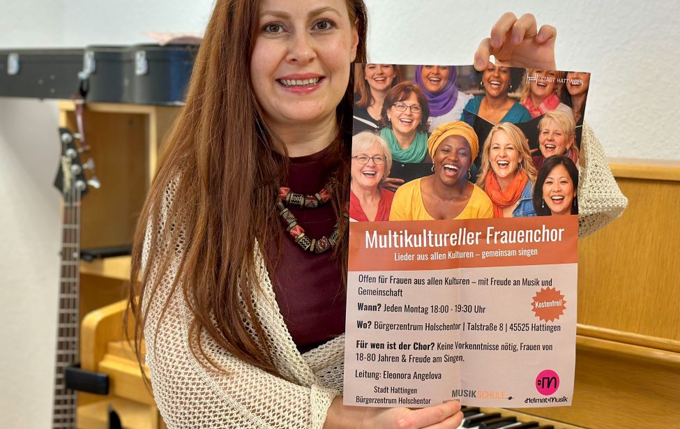 Fotografie von der Chorleiterin, die ein Plakat in der Hand hält