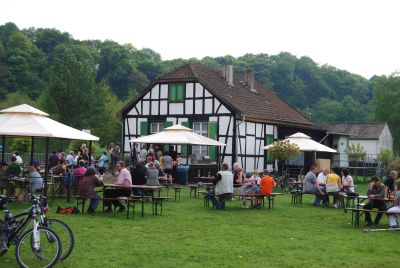 Foto des Schleusenwärterhäuschens in Witten mit Gästen an Tischen