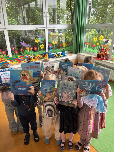 Kinder halten viele Bücher hoch 