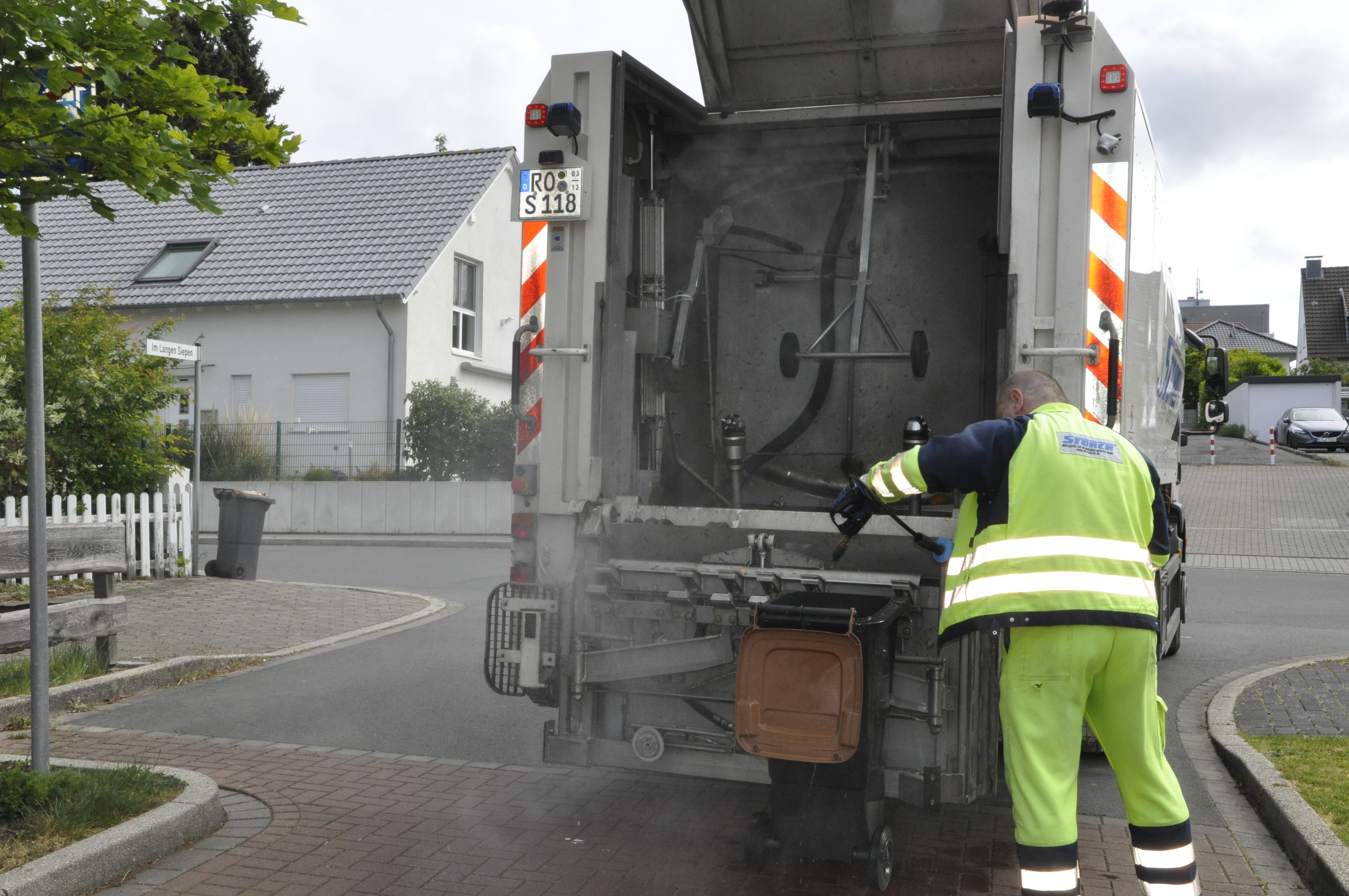 Eine Person reinigt mit dem Spülmobil eine Biotonne