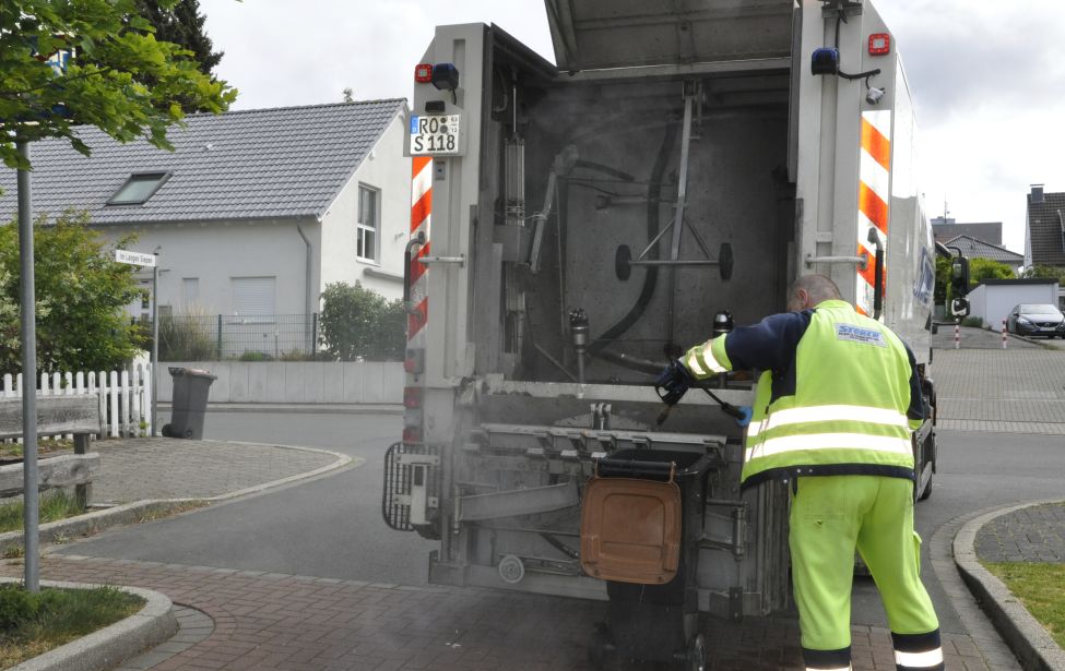 Eine Person reinigt mit dem Spülmobil eine Biotonne