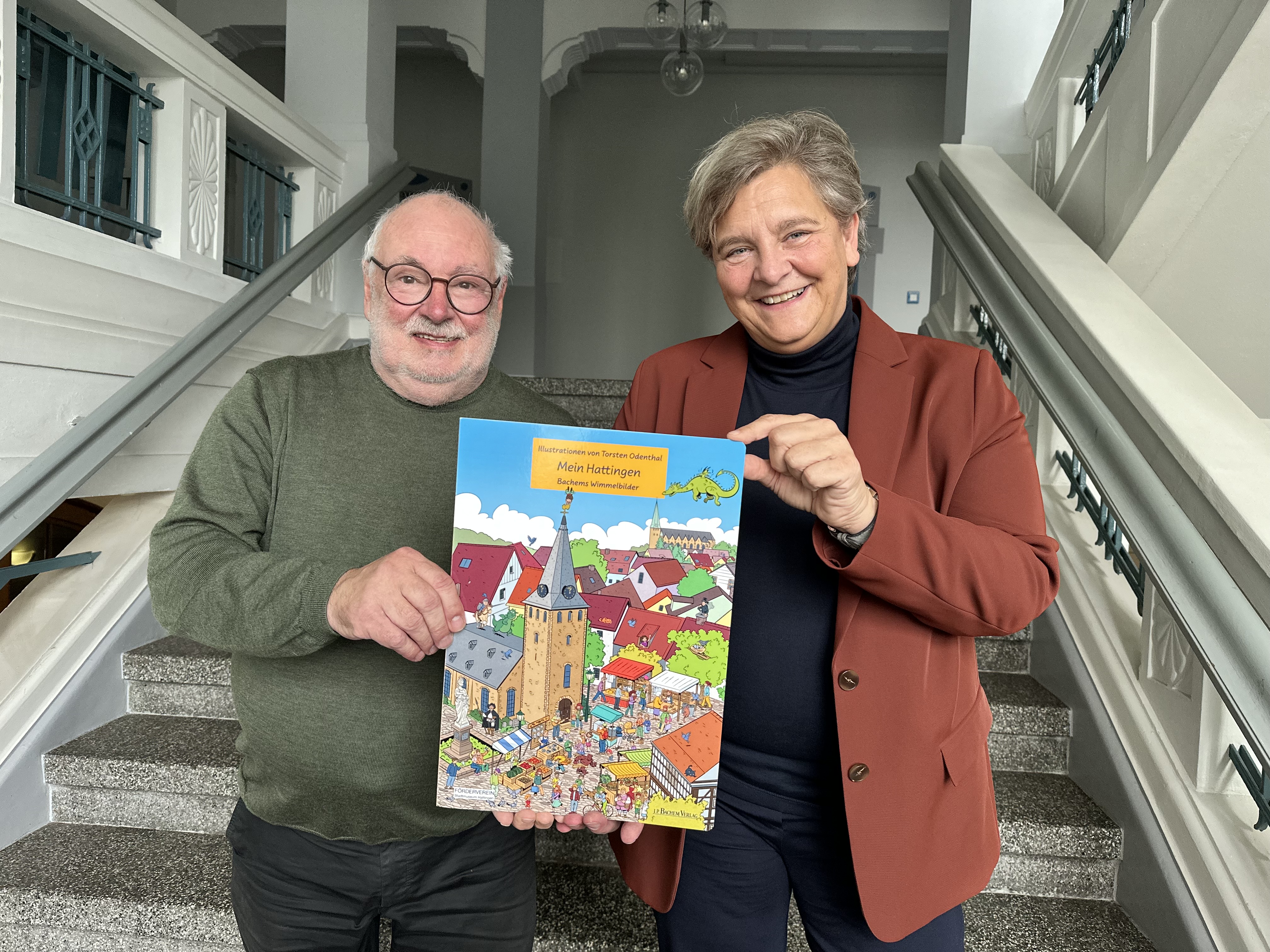 Walter Ollenik überreicht Bürgermeisterin Melanie Witte-Lonsing die ersten Exemplare des Hattinger Wimmelbuches.