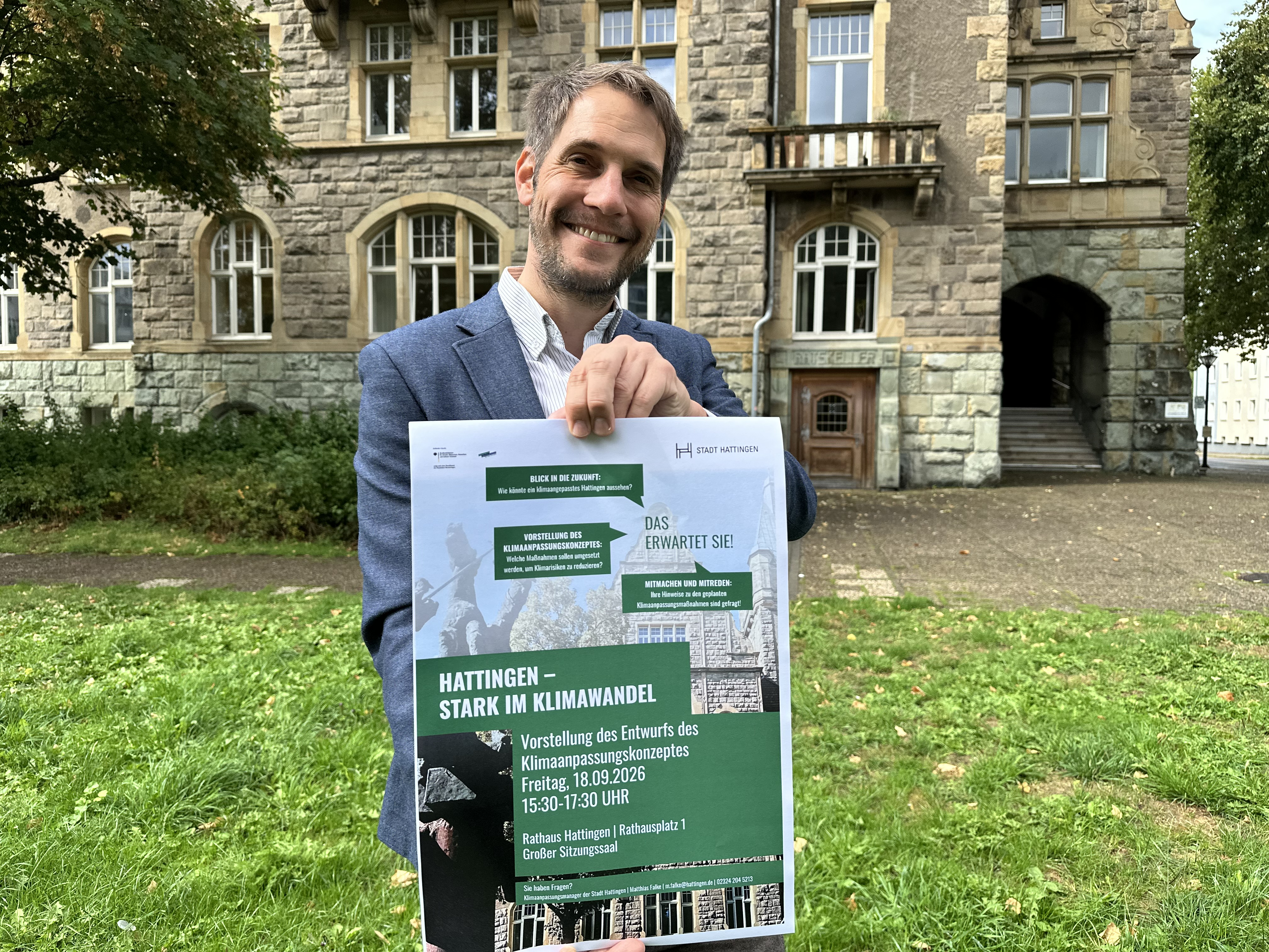Klimaanpassungsmanager Matthias Falke mit dem Plakat zur Informationsveranstaltung vor dem Rathaus 